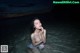 A naked woman sitting in the water at night.