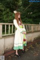 A woman in a white and green dress standing on a bridge.