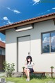 A girl sitting on a bench in front of a house.