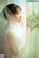 A woman in a wedding dress looking out of a window.