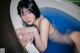 A woman laying in a bathtub with blue water.