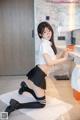 A woman in a school uniform posing in front of a sink.