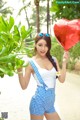 A woman holding a red heart shaped balloon in her hand.