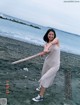 A woman holding a baseball bat on a beach.