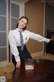 A woman in a white shirt and tie standing next to a table.