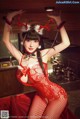 A woman in a red lingerie posing in a kitchen.