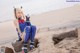 A woman sitting on top of a rock on a beach.