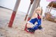 A woman in a blue and red outfit sitting on a beach.