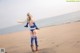 A woman in a bikini standing on a beach next to the ocean.