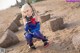 A woman in a blue and red outfit crouching on a sandy beach.