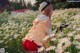 A woman in a field of daisies with a hat on.