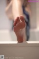 A woman standing in a bathtub with her bare feet.