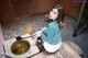 A woman sitting on a wooden bench next to a bowl of water.