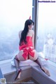 A woman in a red dress sitting on a window sill.