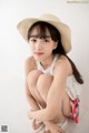 A young woman wearing a straw hat sitting on the floor.