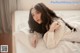 A woman laying on top of a bed in a white shirt.