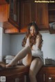 A woman sitting on top of a kitchen counter.