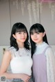 Two young women standing next to each other in a room.