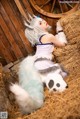 A woman in a bunny costume laying on a pile of hay.