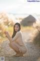 A woman sitting on a dirt road holding a dandelion.