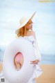 A woman in a white dress and hat holding a white inflatable ring.