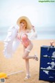 A woman in a pink bikini and a straw hat on the beach.