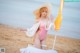 A woman in a pink bathing suit and hat on the beach.