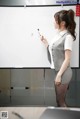 A woman standing in front of a whiteboard writing on it.