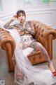 A woman with tattoos sitting on a brown leather chair.