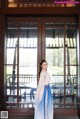 A woman in a blue and white dress standing in front of a door.