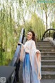 A woman in a blue and pink hanbok standing on a bridge.