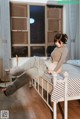 A woman sitting on a bed in a bedroom.