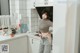 A woman standing in a kitchen next to a refrigerator.