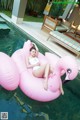 A woman laying on an inflatable flamingo floating in a pool.