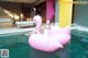 A woman sitting on an inflatable flamingo floating in a pool.