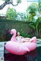 A woman laying on an inflatable pink flamingo in a pool.